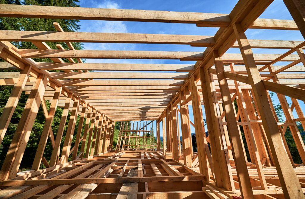 Wooden frame house under construction near forest.